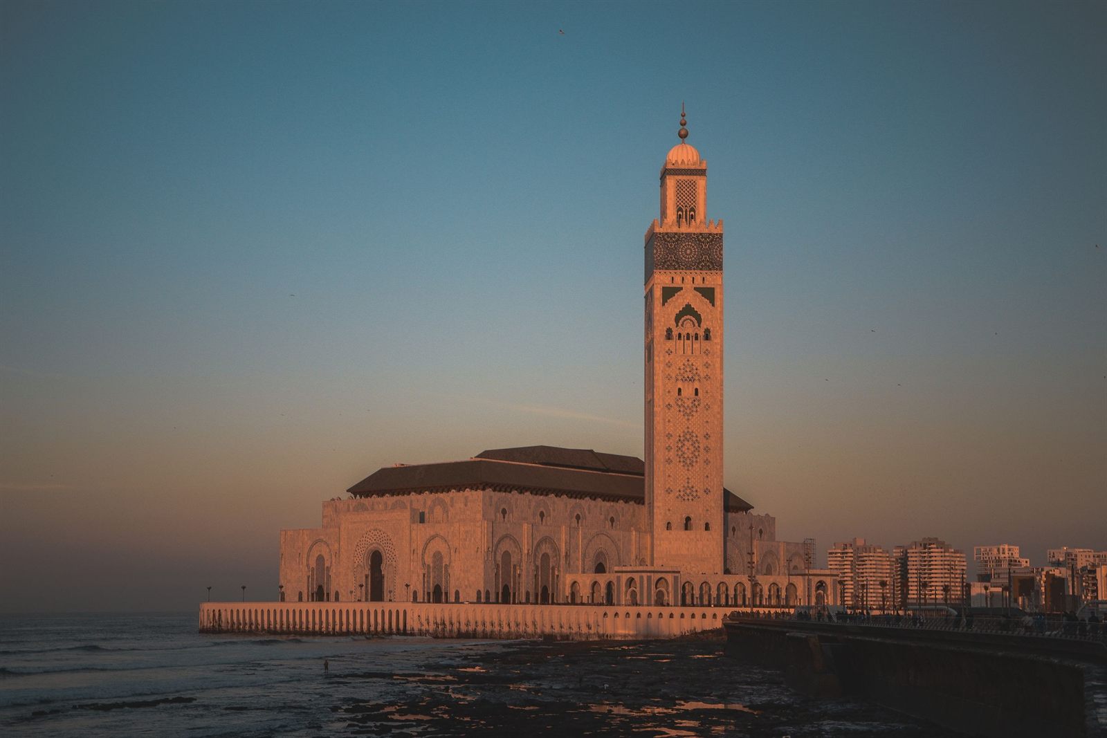 Hassan II Mosque and its minaret beside the sea in Casablanca at dusk