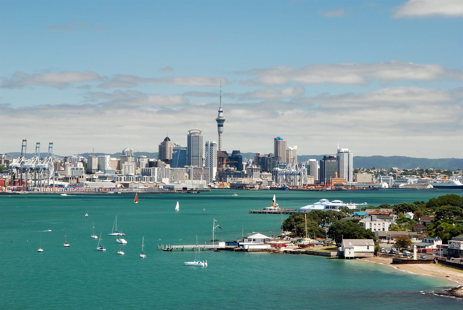 Auckland skyline and Sky Tower above a marina on a sunny day